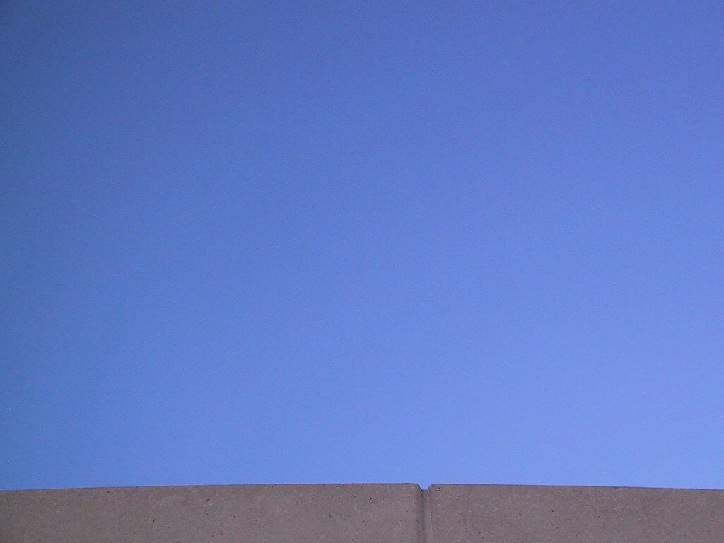 Blue sky over the edge of a wall, framed with nothing extra.