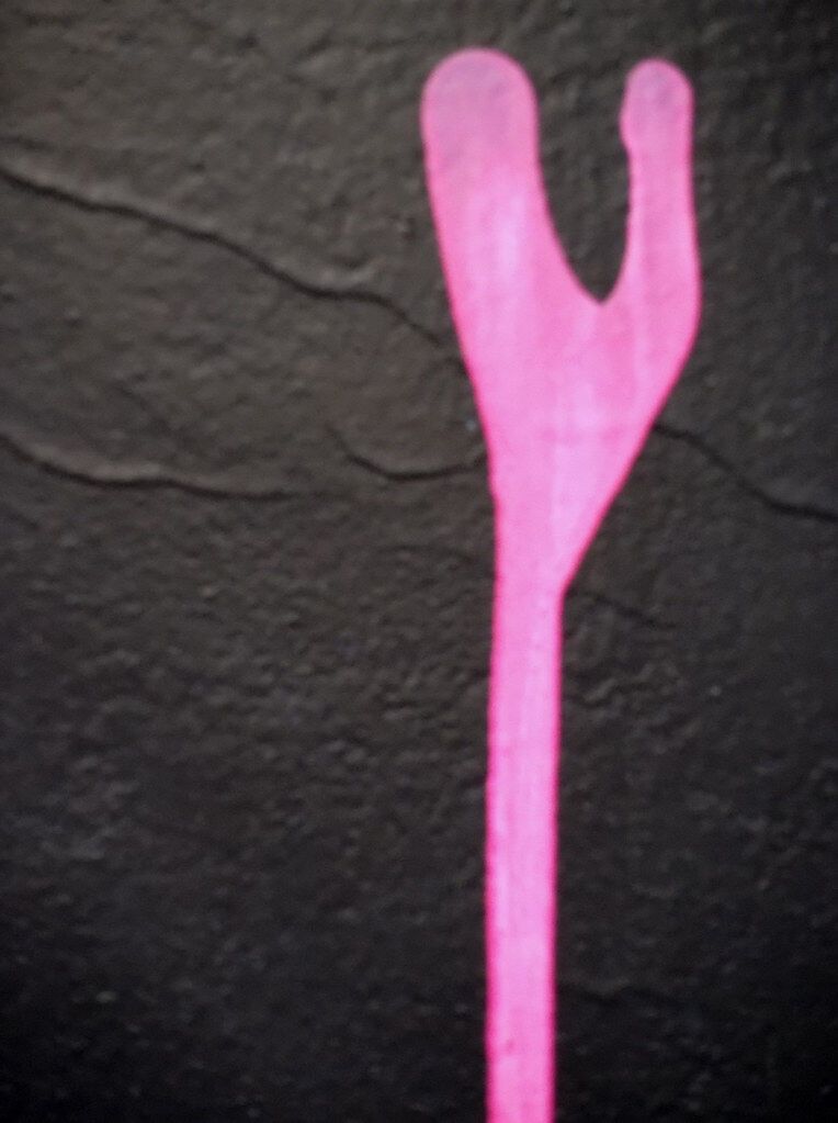 A pink fork shape on black, seen before it has a name.