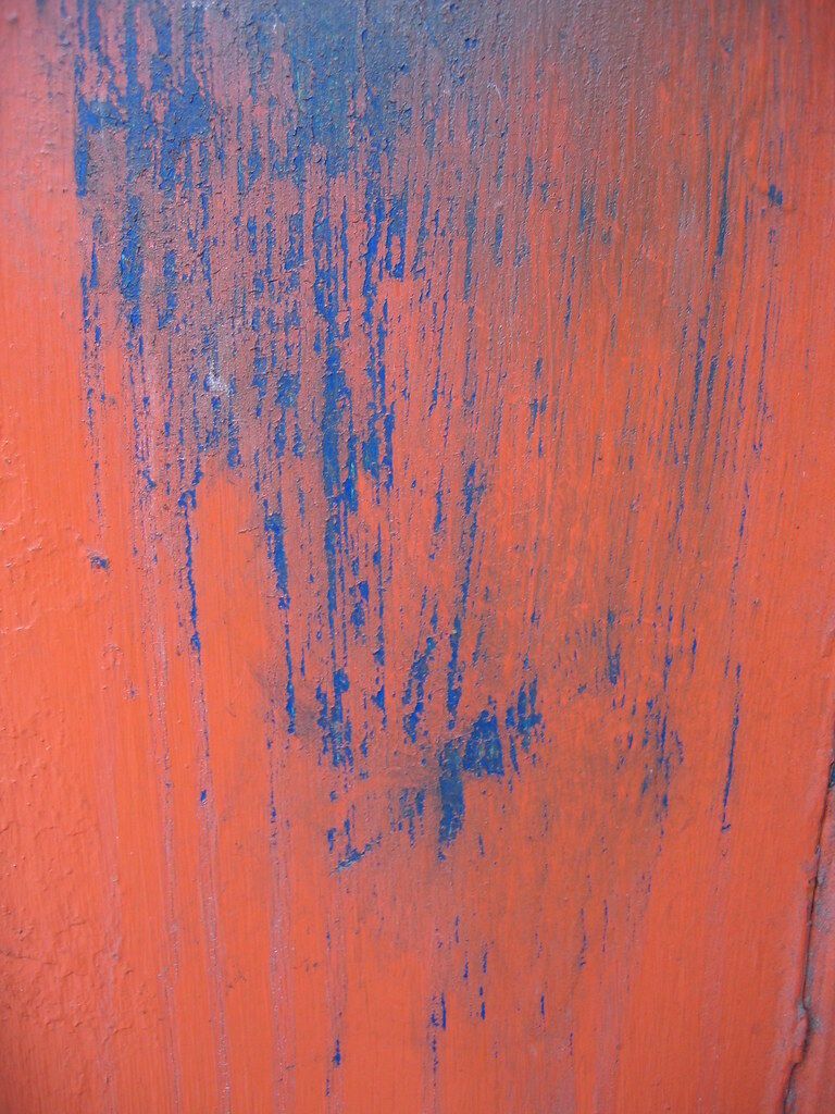 Blue paint run down an orange door.